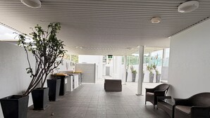 A covered outdoor area with a seating arrangement, potted plants, and a view of the surrounding landscape.