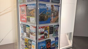 A promotional display rack with various travel brochures and guides.