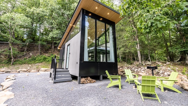 Eine moderne Holzhütte mit großen Fenstern, einem Holzdach und Sitzgelegenheiten im Freien.
