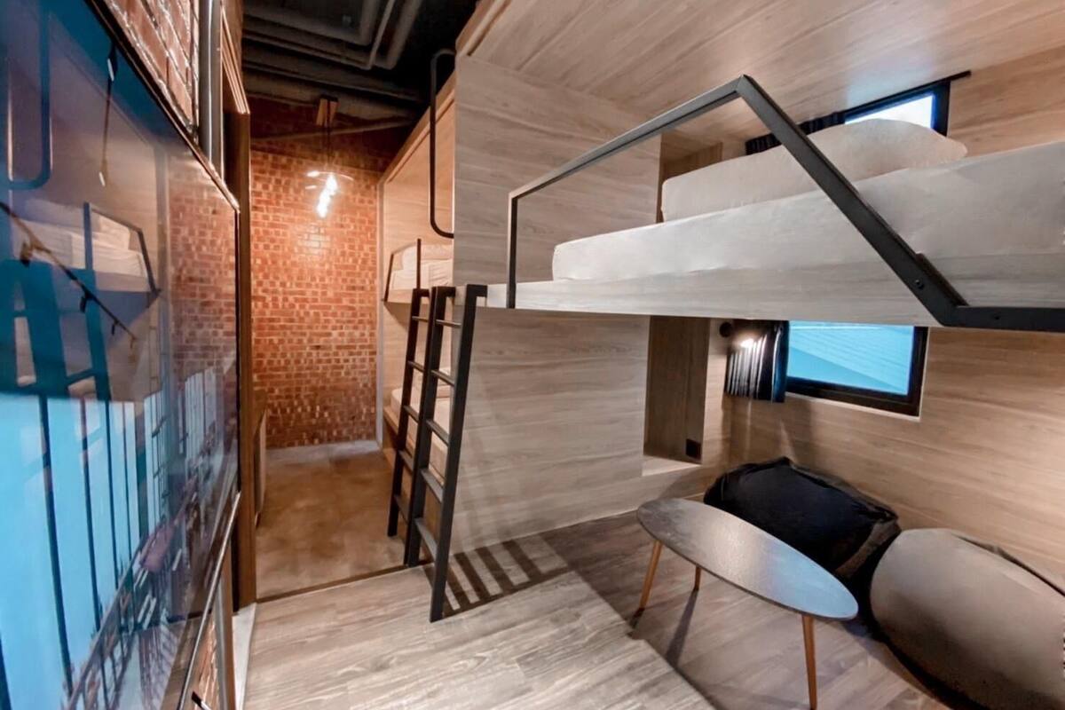 Un interior moderno con una escalera, un pequeño rincón de descanso y una pared de ladrillo.