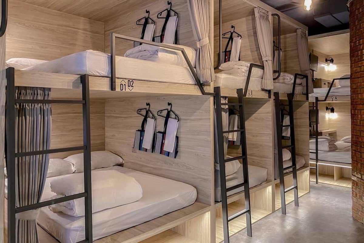 Habitación con literas, paredes de madera, una escalera y ropa colgada.