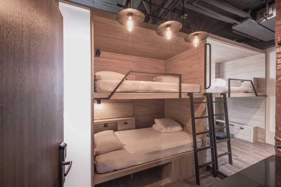 A bunk bed room with wooden walls, a ladder, and a desk.