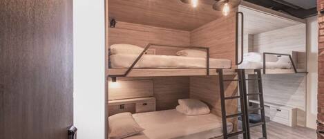 A bunk bed room with wooden walls, a ladder, and a desk.
