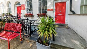 Un edificio con ventanas arqueadas, una puerta roja y un cartel que dice 'Welcome'.