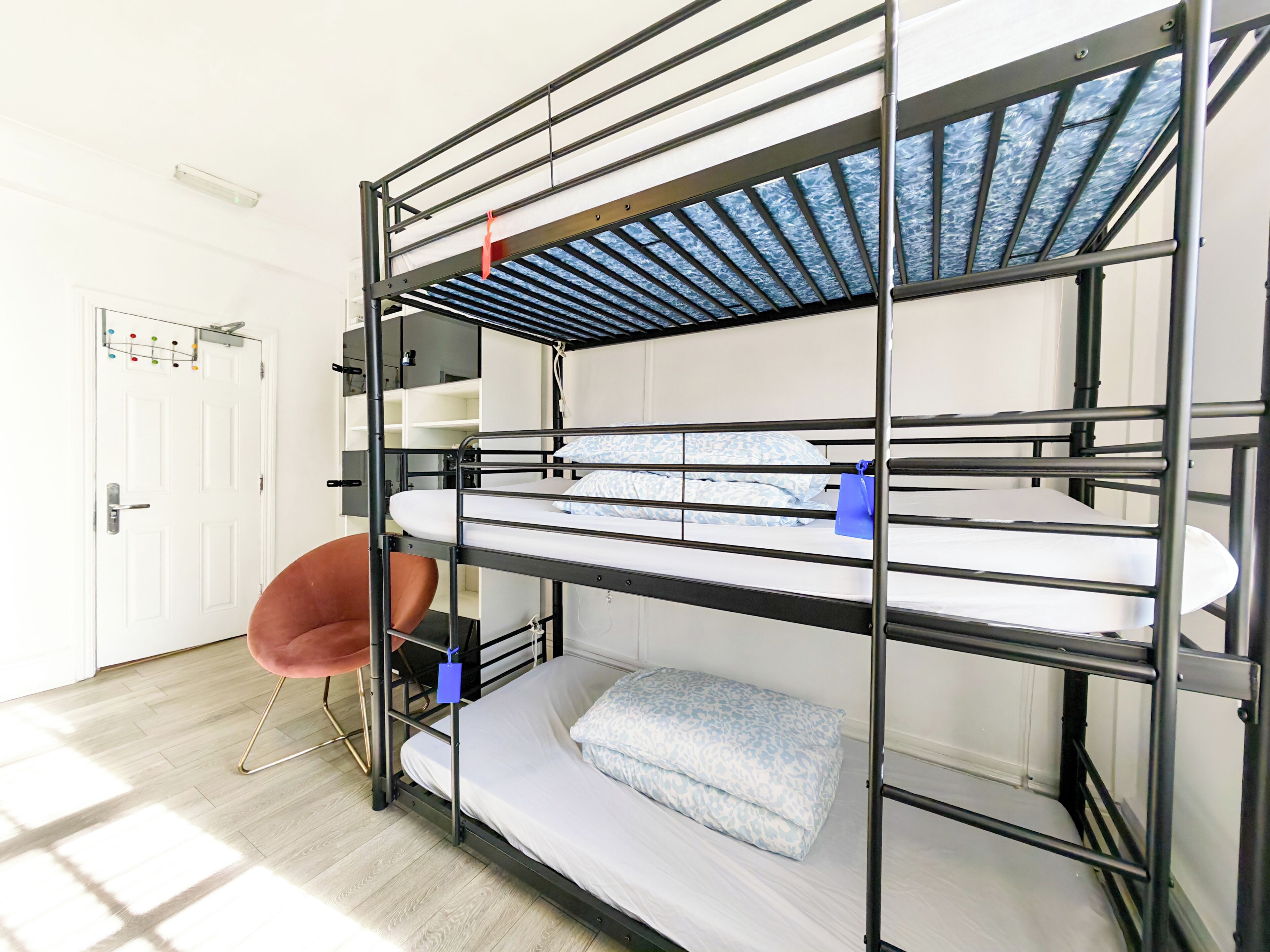 A bunk bed with a metal frame, a white door, and a brown chair.