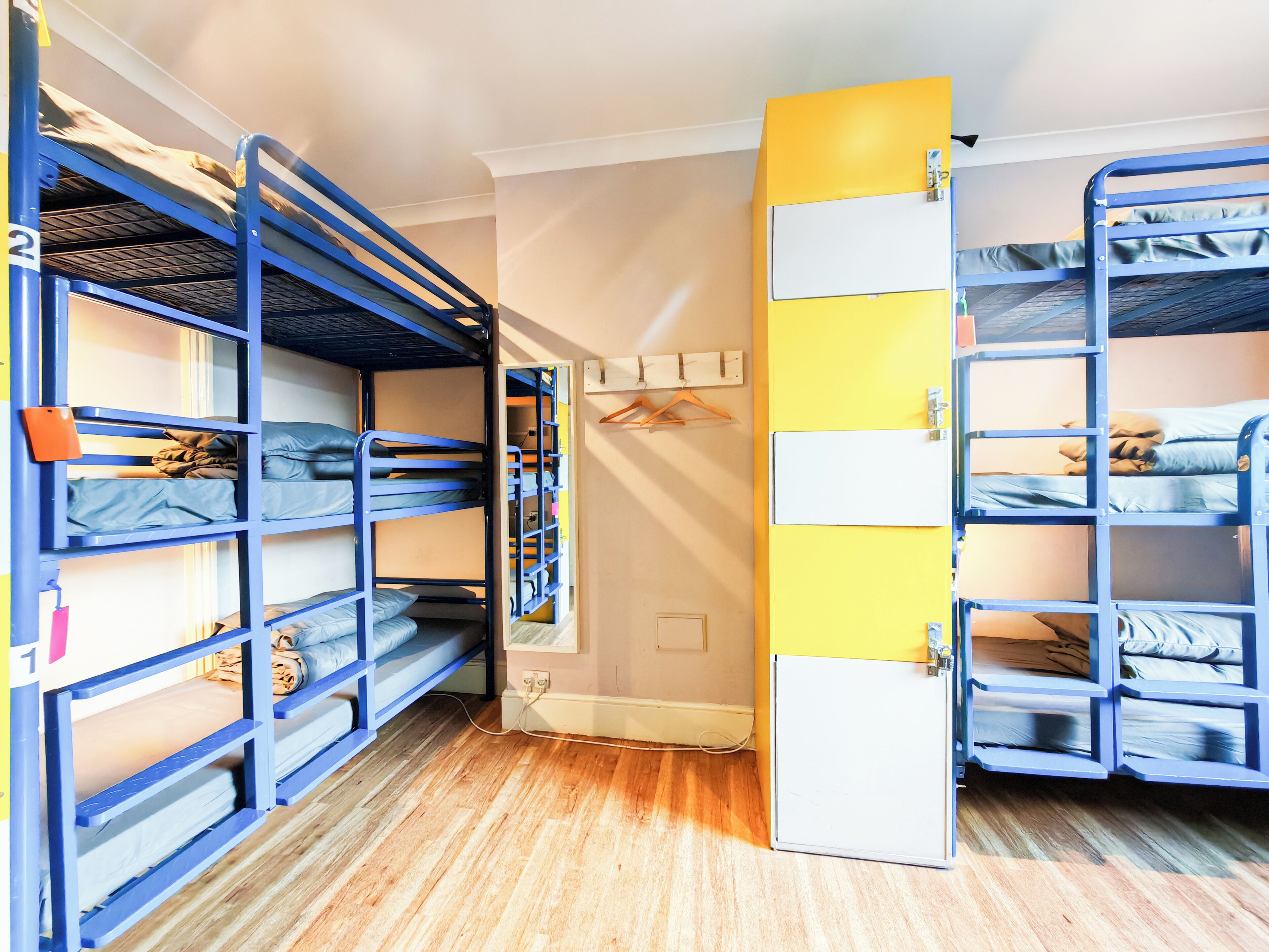 A room with bunk beds, a door, a wall-mounted shelf, and a power outlet.
