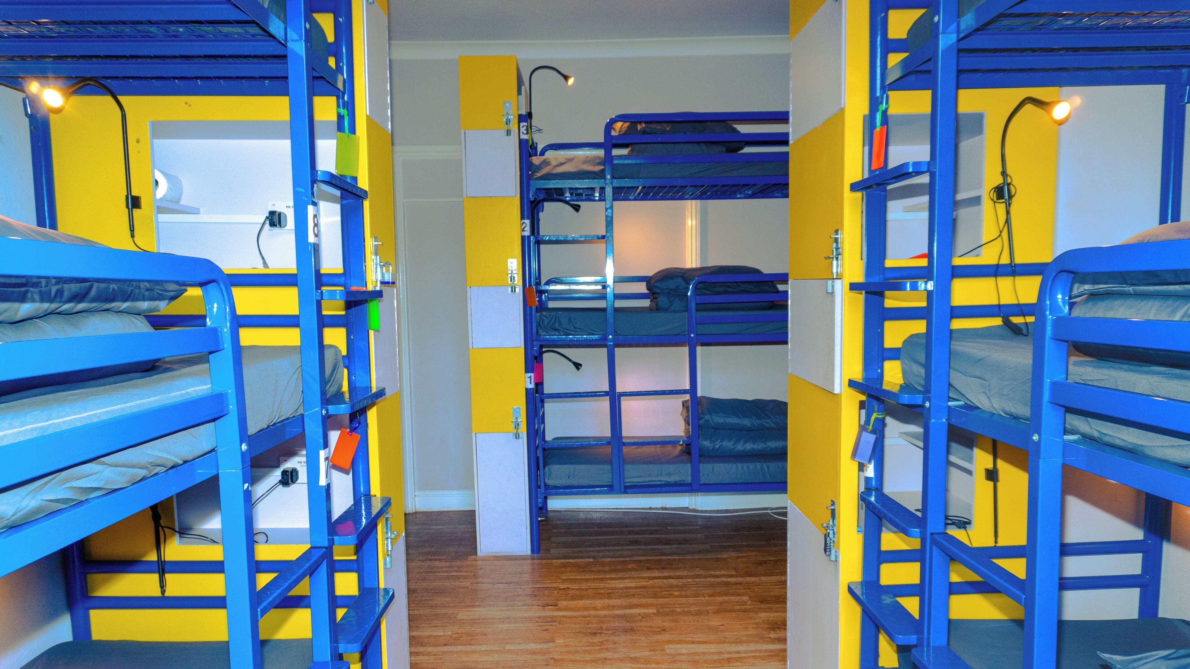 A bunk room with multiple bunk beds, wooden flooring, and a visible door.