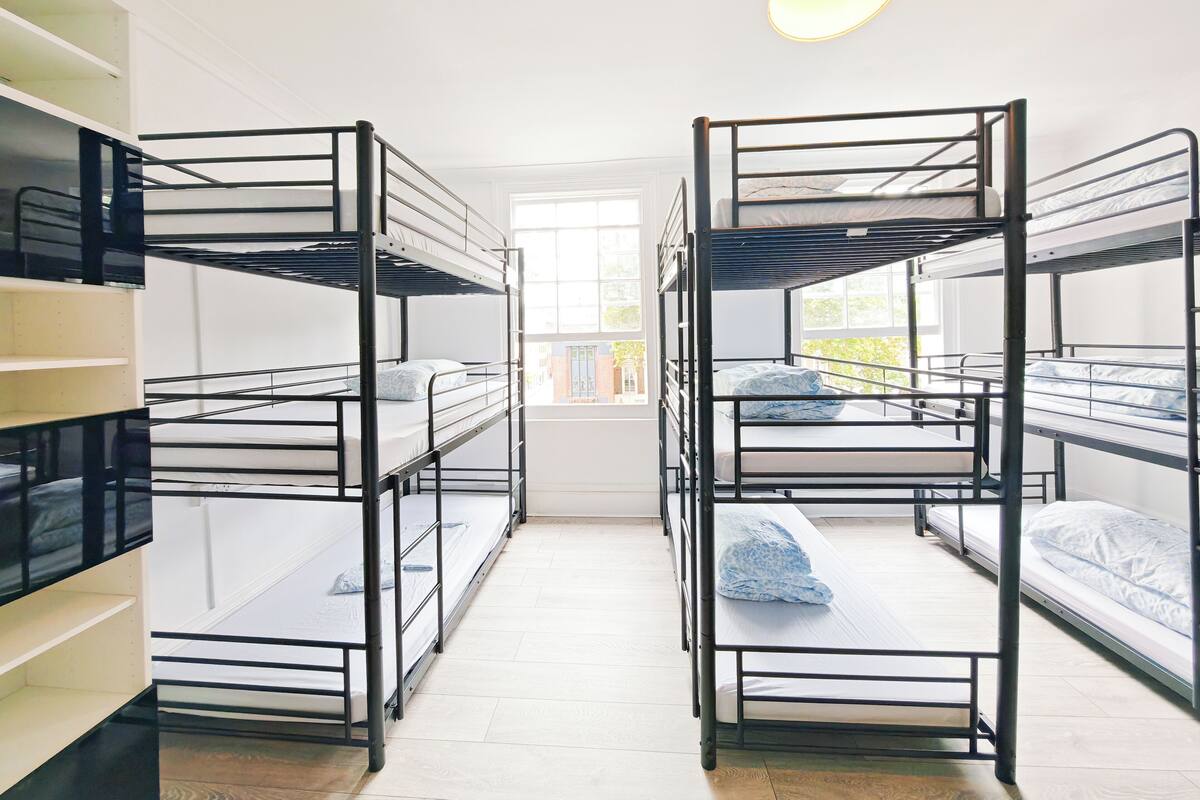 Asuntolan huone, jossa on kerrossängyt, ikkuna ja ovi.