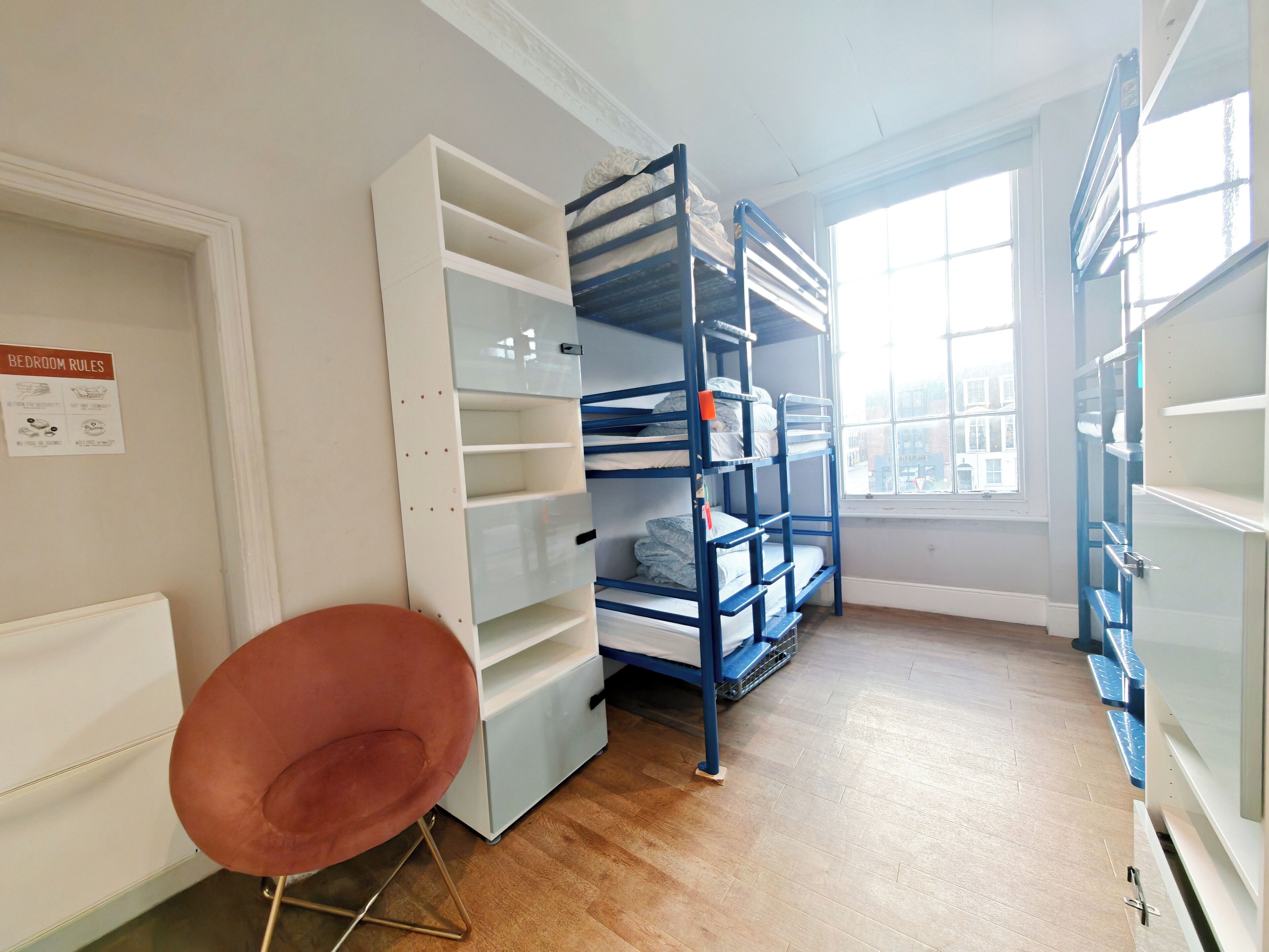 Quarto com beliches, uma cadeira e janela com vista.
