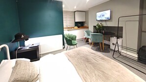 Una habitación de hotel moderna con una cama, un escritorio, dos sillas, un televisor y un radiador.