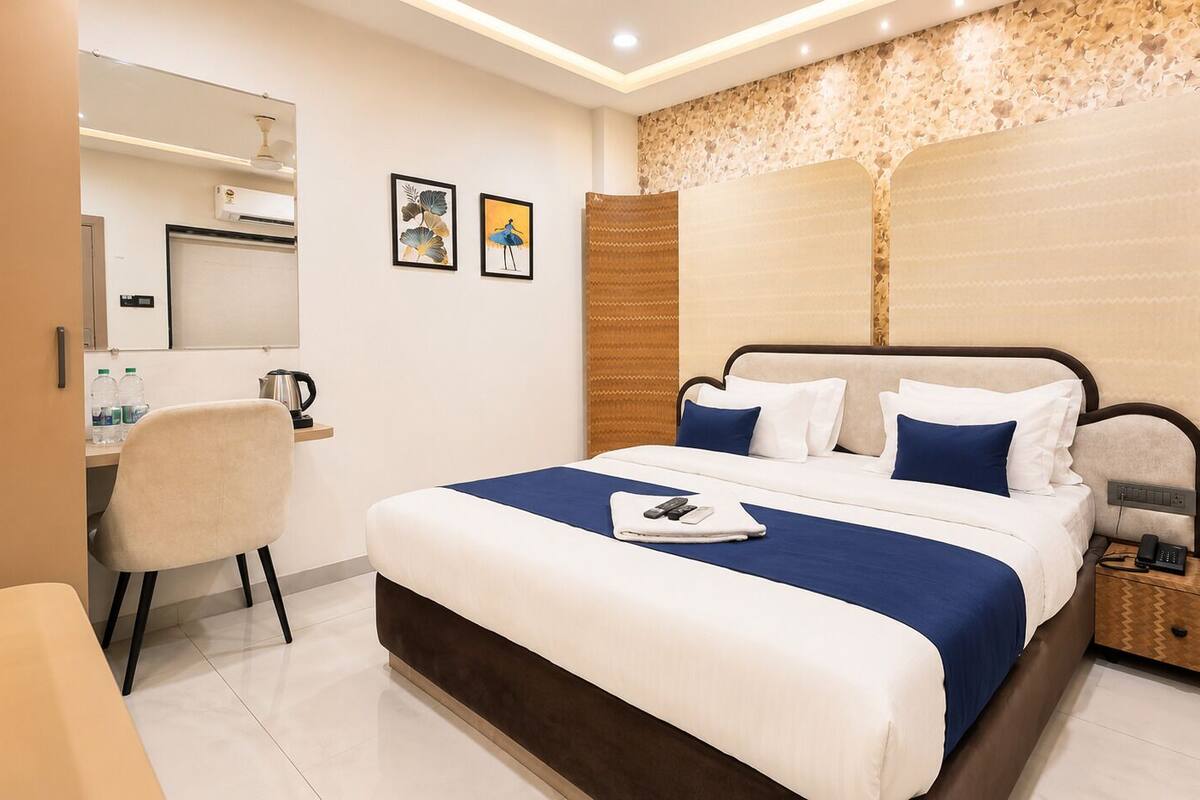 A modern hotel room with a large bed, a desk, and a mirror.