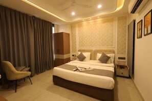 A hotel room with a bed, a chair, a wardrobe, a nightstand, and a ceiling fan. - Hotel Stayspire (Indore)