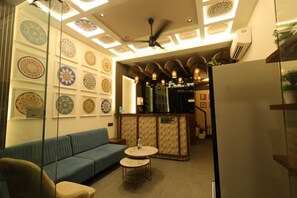 A reception area with a blue sofa, a round table, and patterned wall decorations. - Hotel Stayspire (Indore)