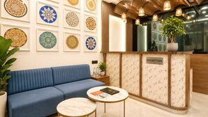A reception area with a blue sofa, a reception desk, and a wall decorated with circular patterns. - Velar Prime Hotel, Vijay Nagar, Indore (Indore)
