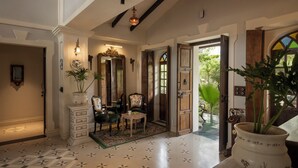 A hallway with a patterned floor, a wooden chair, a table, and a potted plant. - Staymaster Samba Sunset 3BR Pvt Pool (Anjuna)