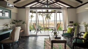 A room with a balcony, a table, chairs, and a view of palm trees. - Staymaster Samba Sunset 3BR Pvt Pool (Anjuna)