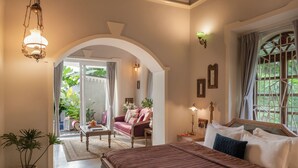 A bedroom with a large bed, a ceiling fan, a chandelier, and a view of the outdoors. - Staymaster Samba Sunset 3BR Pvt Pool (Anjuna)
