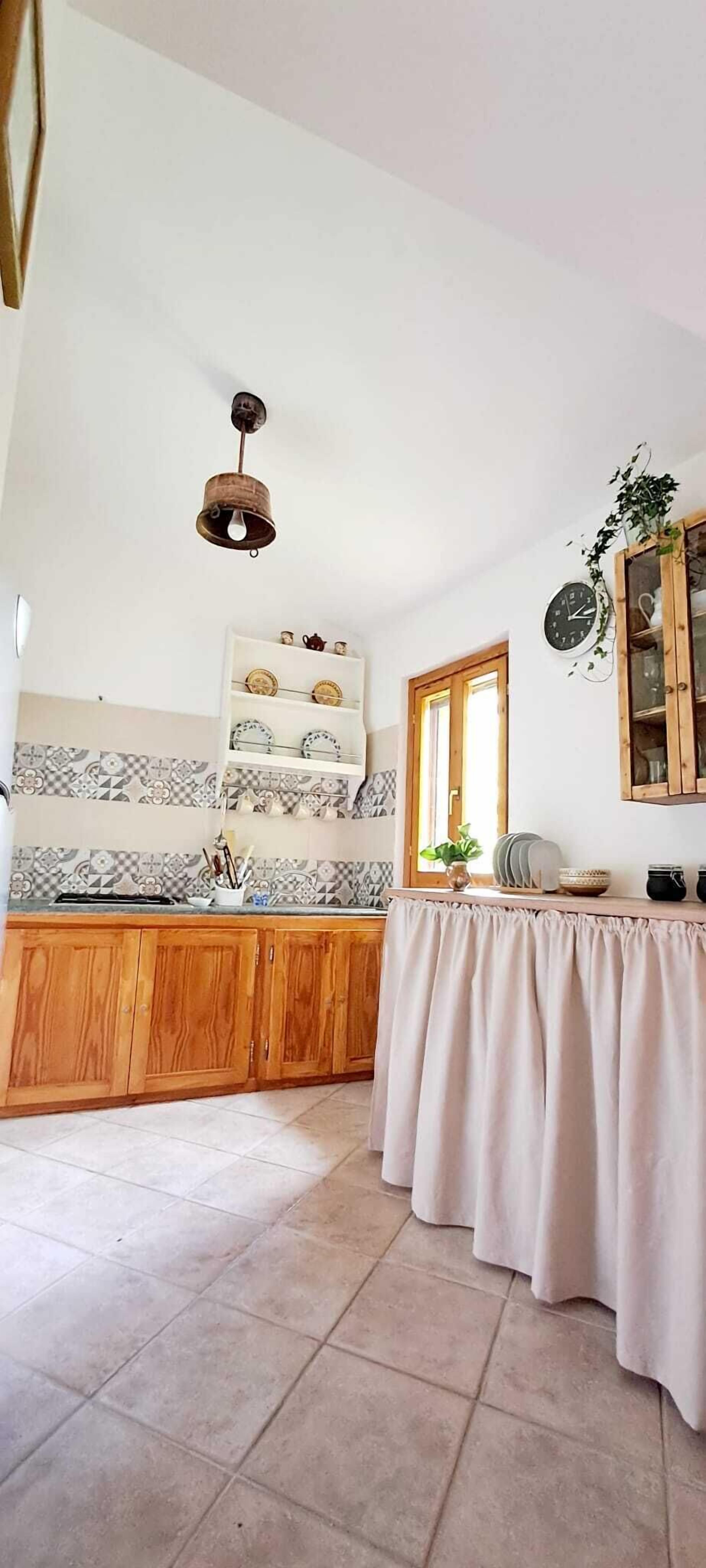 A kitchen with wooden cabinets, a tiled backsplash, a hanging light fixture, and a window.