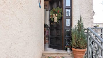 A door with a wreath, a potted plant, and a doormat.