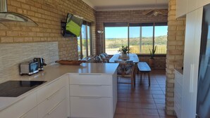 Una cocina con pared de ladrillo, una ventana con vistas, una mesa de comedor con sillas y un refrigerador.