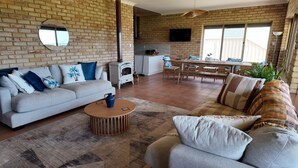 Una sala de estar con sofá, mesa de centro y chimenea. Cuenta con una zona de comedor con mesa y sillas.