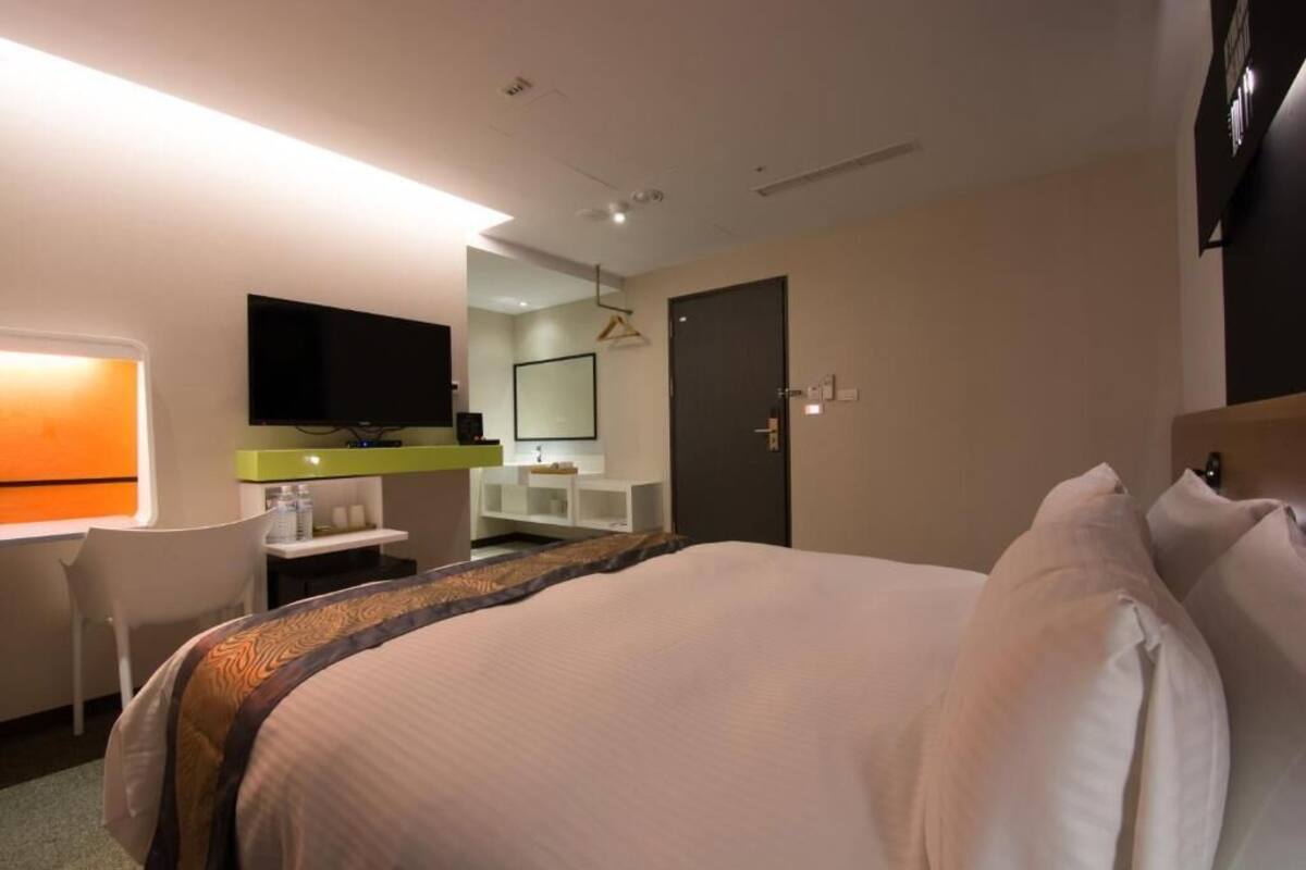 Ein Hotelzimmer mit Bett, Schreibtisch, Stuhl, Fernseher und Bad.