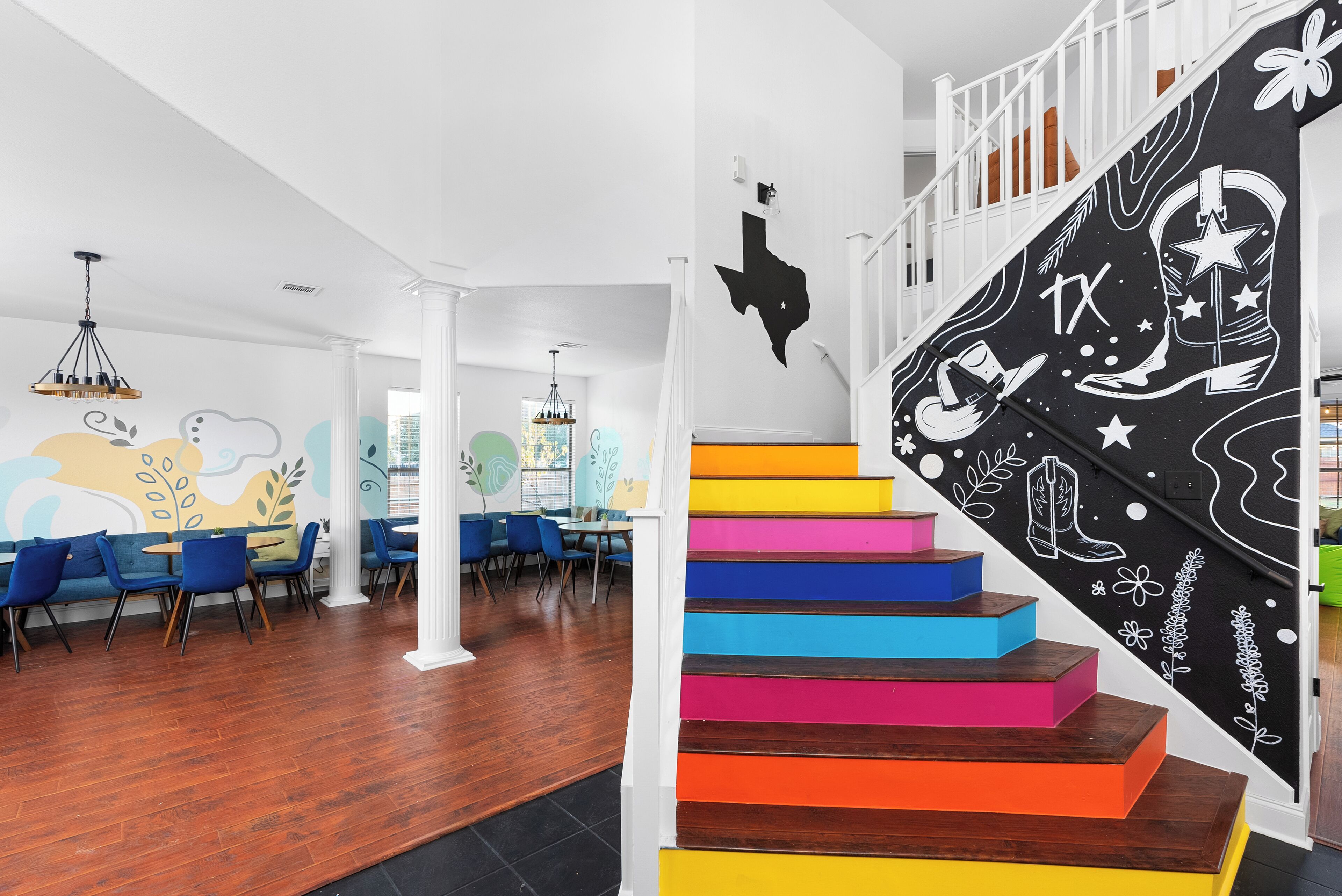 A staircase with colorful steps, a white railing, and a wall with a black and white design.