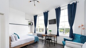Una habitación moderna con cama, escritorio, silla y sofá.