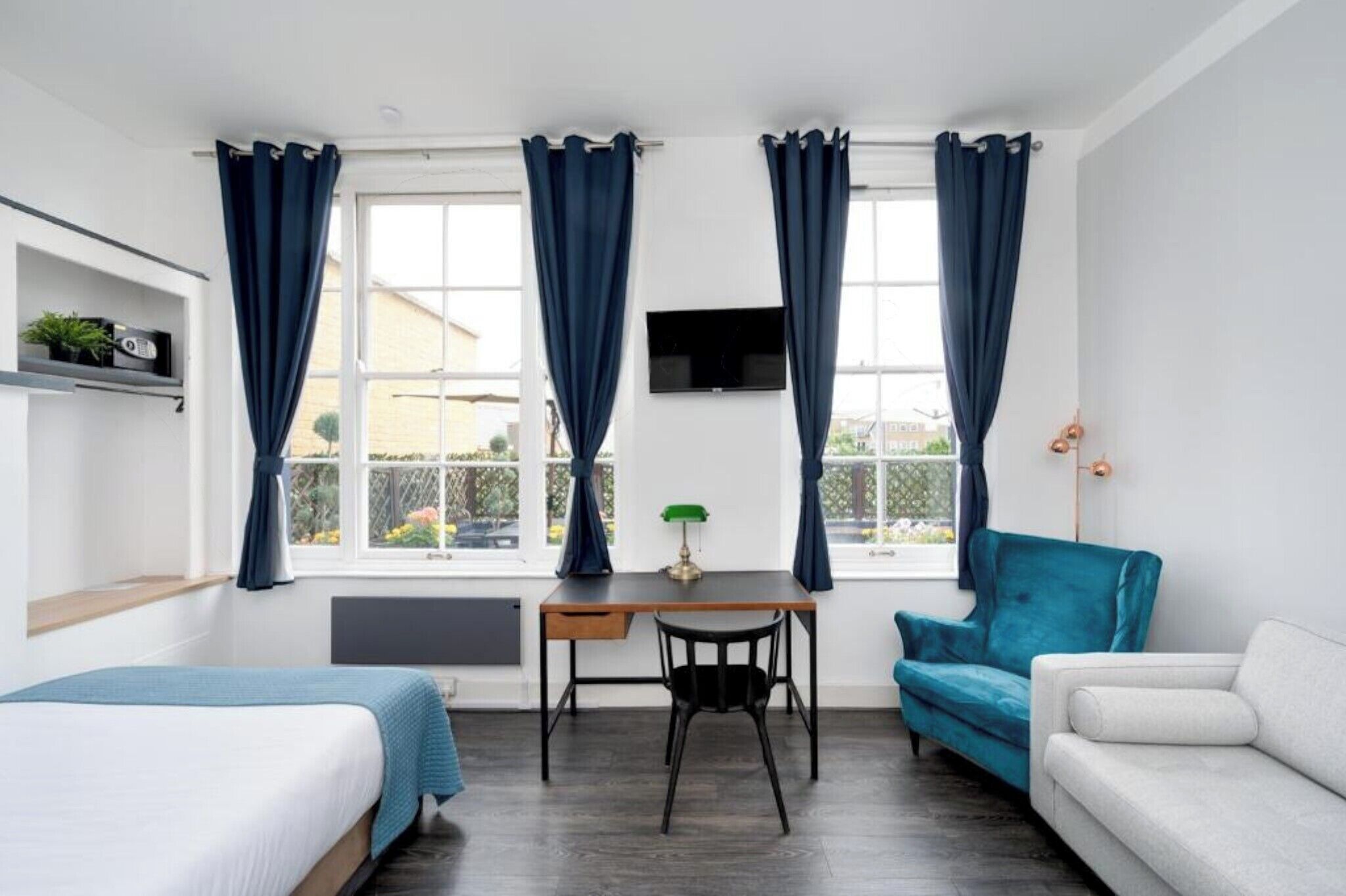 Ein Zimmer mit zwei Betten, einem Schreibtisch, einem Sessel, einem Fernseher und einem Sofa.