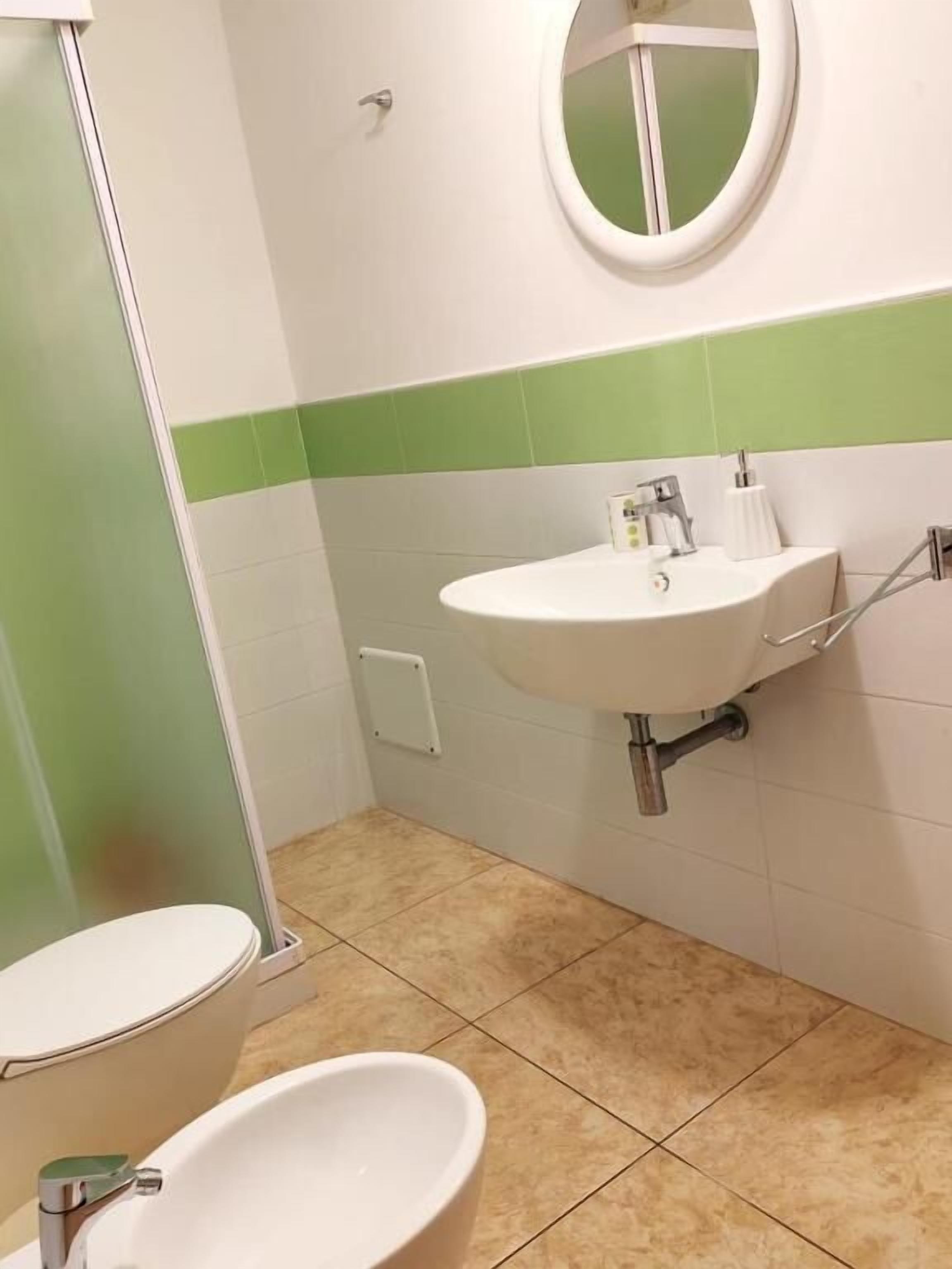 A bathroom with a toilet, a sink, and a mirror.