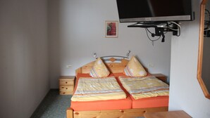 A bedroom with a bed, a television mounted on the wall, and a small bedside table. - 2nd standard double room (Benny) in a quiet location in Görlitz (Görlitz)