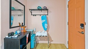 Une salle de bain avec un miroir, une étagère avec des casques, un porte-serviettes et une porte.