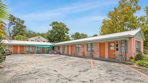 A row of pink motel buildings with a large parking lot in front. - Travel Back to the 50s- Renovated Motel Gem (St. Augustine)