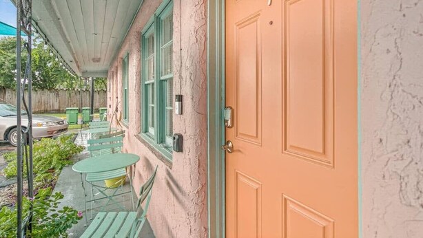 A porch with a green table and chairs, a car parked outside, and a door with the number 7. - Dive Into the 50s- Restored Motel in St Augustine (St. Augustine)