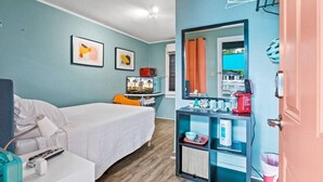 A room with a bed, a desk with a computer, a mirror, and a shelf with various items. - Dive Into the 50s- Restored Motel in St Augustine (St. Augustine)