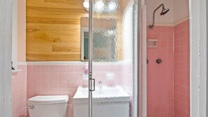 A bathroom with a toilet, a sink, and a shower enclosure. - Dive Into the 50s- Restored Motel in St Augustine (St. Augustine)