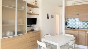 A compact kitchen with a dining area, wooden cabinets, and a television on a stand. - SE219 - Senigallia, two-bedroom apartment with a beautiful seafront terrace (Senigallia)