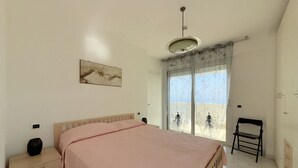 A bedroom with a bed, a nightstand, a chair, a window with a view, and a ceiling light. - SE219 - Senigallia, two-bedroom apartment with a beautiful seafront terrace (Senigallia)