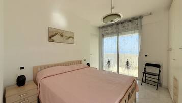 A bedroom with a bed, a nightstand, a chair, a window with a view, and a ceiling light.