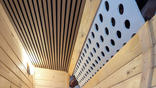 Un sauna avec des murs en bois, un plafond incliné et un banc.