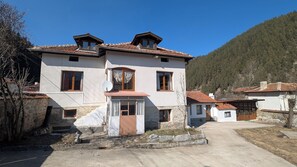 Ein zweistöckiges Gebäude mit einer Stein-Fassade, zahlreichen Fenstern und einer kleinen Veranda.
