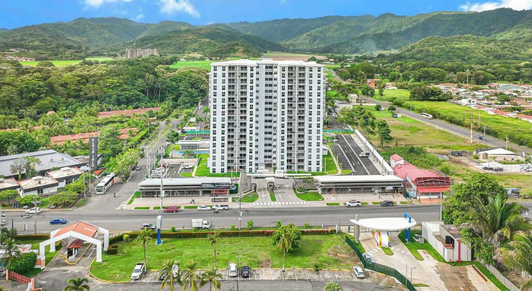 Un hotel moderno de gran altura, con varios pisos, un estacionamiento y una carretera en primer plano.