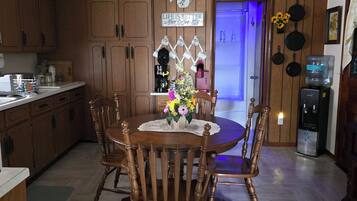 A kitchen with wooden cabinets, a dining table with chairs, a ceiling fan, and a refrigerator.