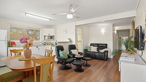 Ein modernes Wohnzimmer mit Essbereich, einer Küche und einem großen Fenster.