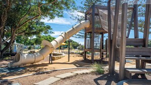 Ein Spielplatz mit Rutsche, Klettergerüsten und einem Holzspielhaus.