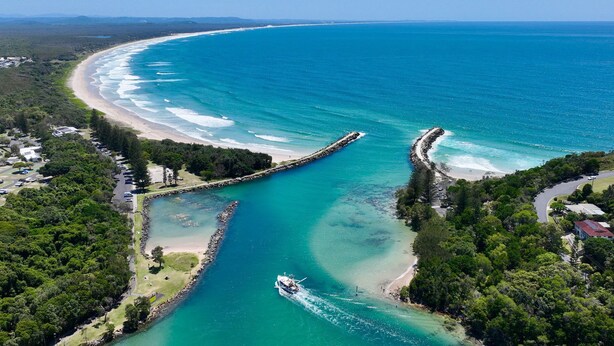 Eine Luftaufnahme einer Küstenregion mit einer gewundenen Straße, einem Strand und einem Boot auf dem Wasser.