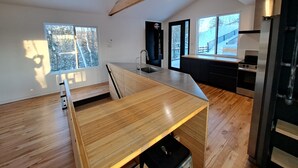 A modern kitchen with wooden flooring, a built-in island, and a large window.