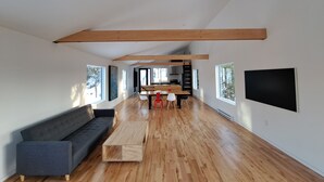A spacious living area with a sofa, a wooden coffee table, and a kitchen in the background.