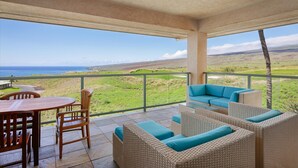 Un espace extérieur abrité, doté d’une table et de chaises, de meubles en osier et offrant une vue sur le paysage.