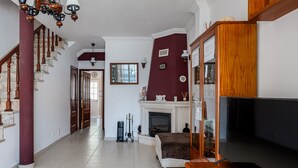 A living room with a fireplace, a television, and a staircase. - 'Alojamento Local Família Coelho' House with Wi-Fi (Quinta do Conde)